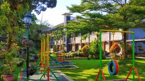 A playground with colorful equipment, surrounded by well-maintained grass and trees. - Hotel Bahtera PT.Pelni (Megamendung)