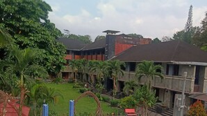A swimming pool area with multiple pools, a children's play area, and a building with a red roof in the background. - Hotel Bahtera PT.Pelni (Megamendung)