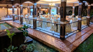 An indoor dining area with tables and chairs, a fountain, and decorative columns. - Hotel Bahtera PT.Pelni (Megamendung)