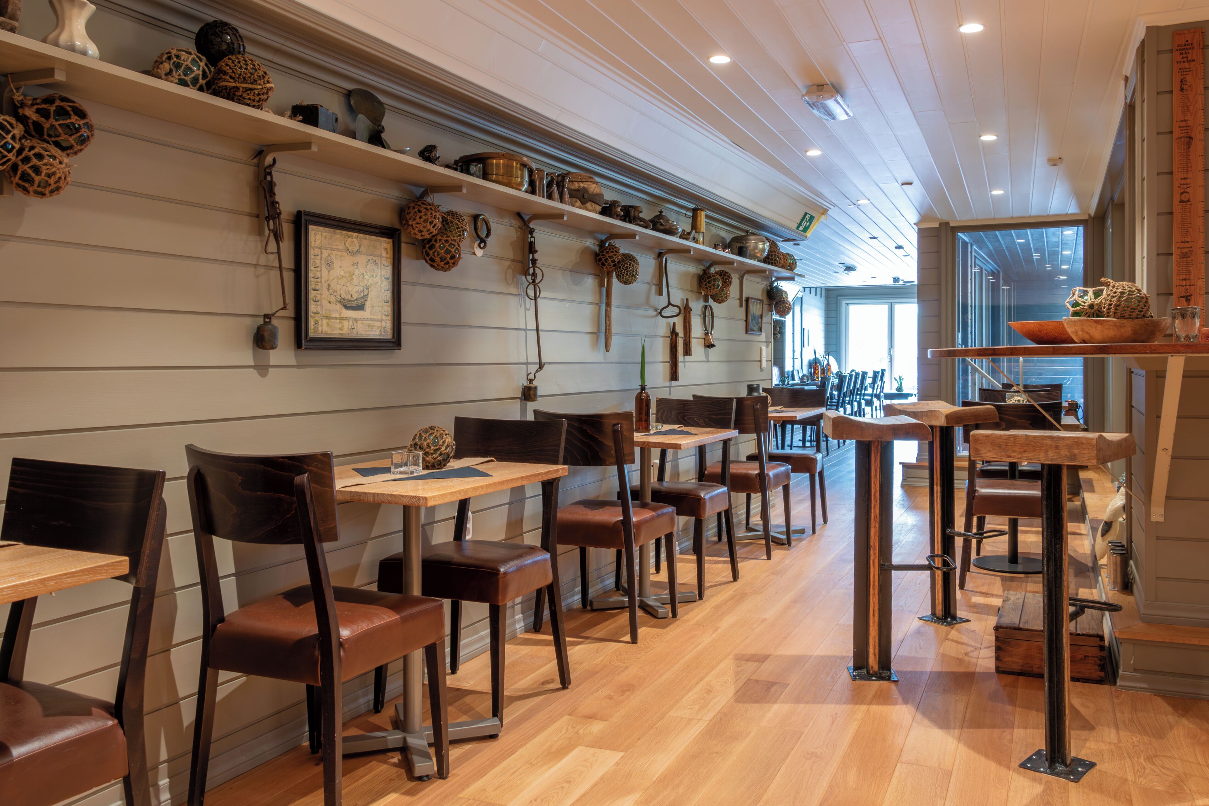 A restaurant interior with wooden floors, brown leather chairs, and shelves with decorative items.