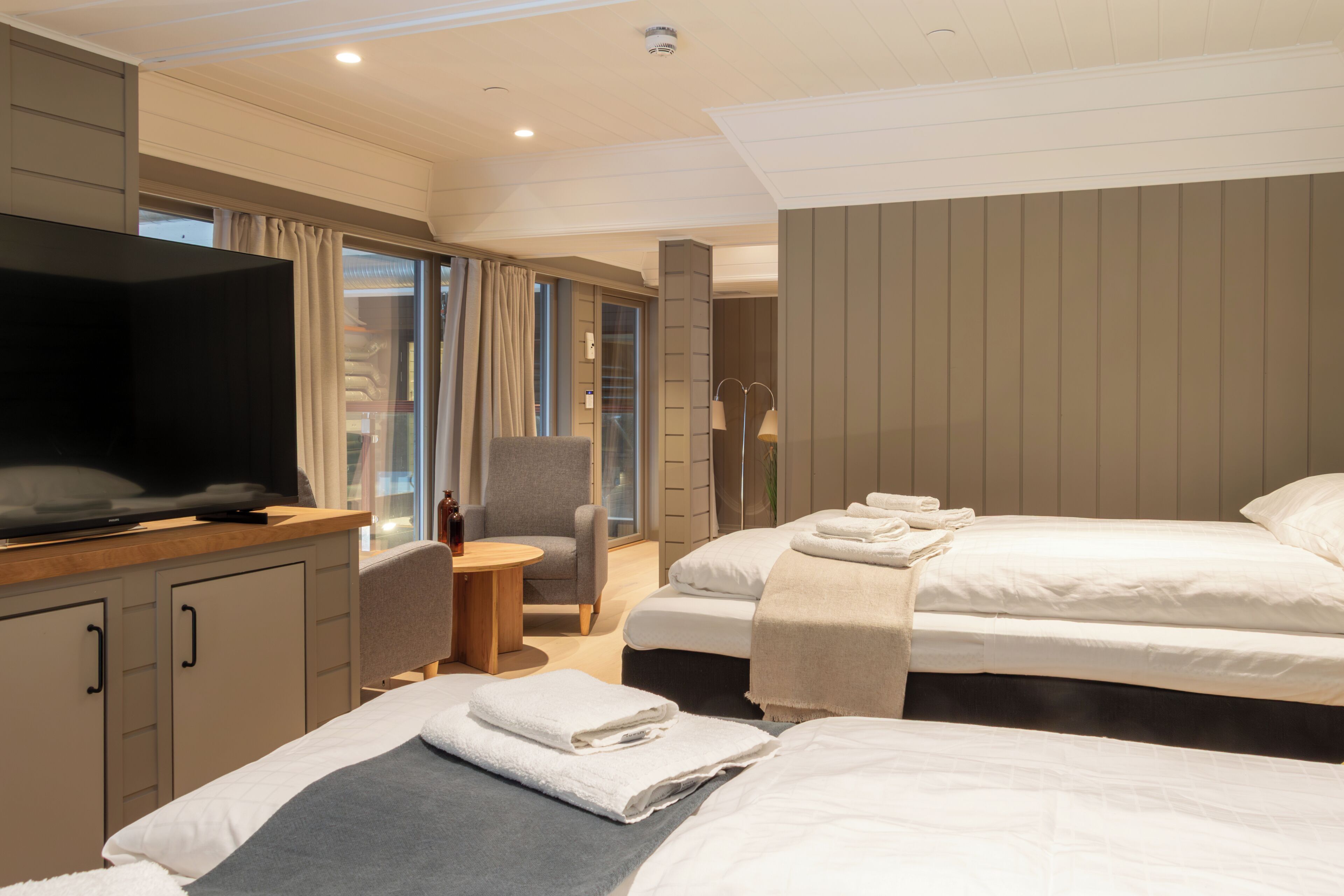 Een hotelkamer met een televisie, twee bedden, een bureau en een stoel.
