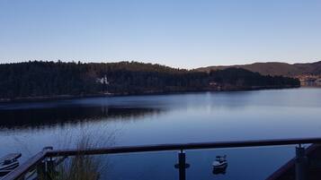 A lake with a dock and boats, surrounded by forested hills and a clear sky.