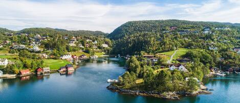 A lakeside village with houses along the water's edge, a small dock, and a bridge connecting the areas.