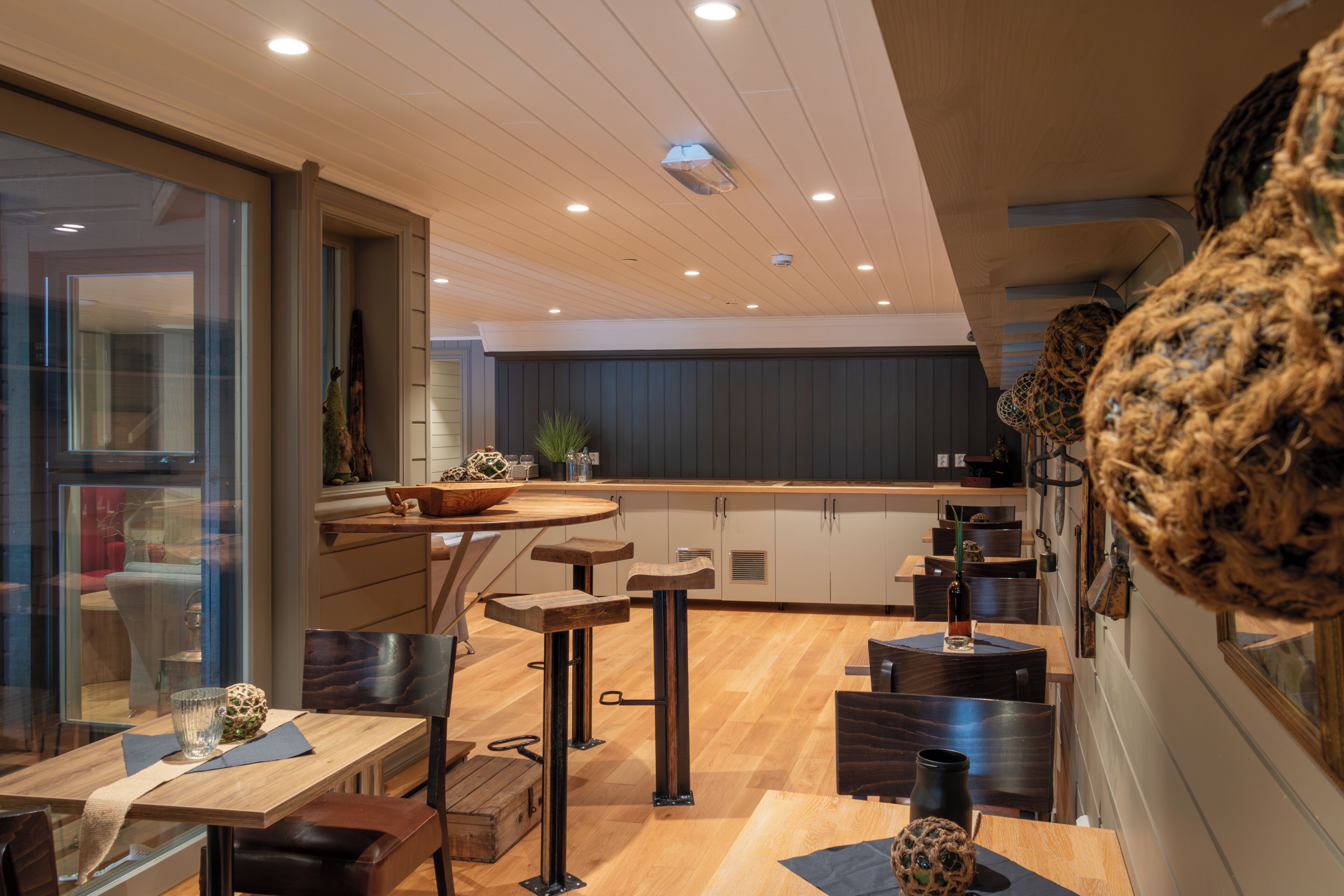 Een moderne keuken met houten aanrecht, een eethoek met krukken, en uitzicht op de aangrenzende woonruimte.