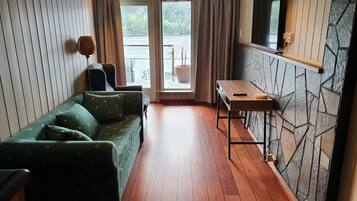 Una habitació acollidora amb un sofà verd, una taula petita i vistes a un llac a través d'una porta de vidre.