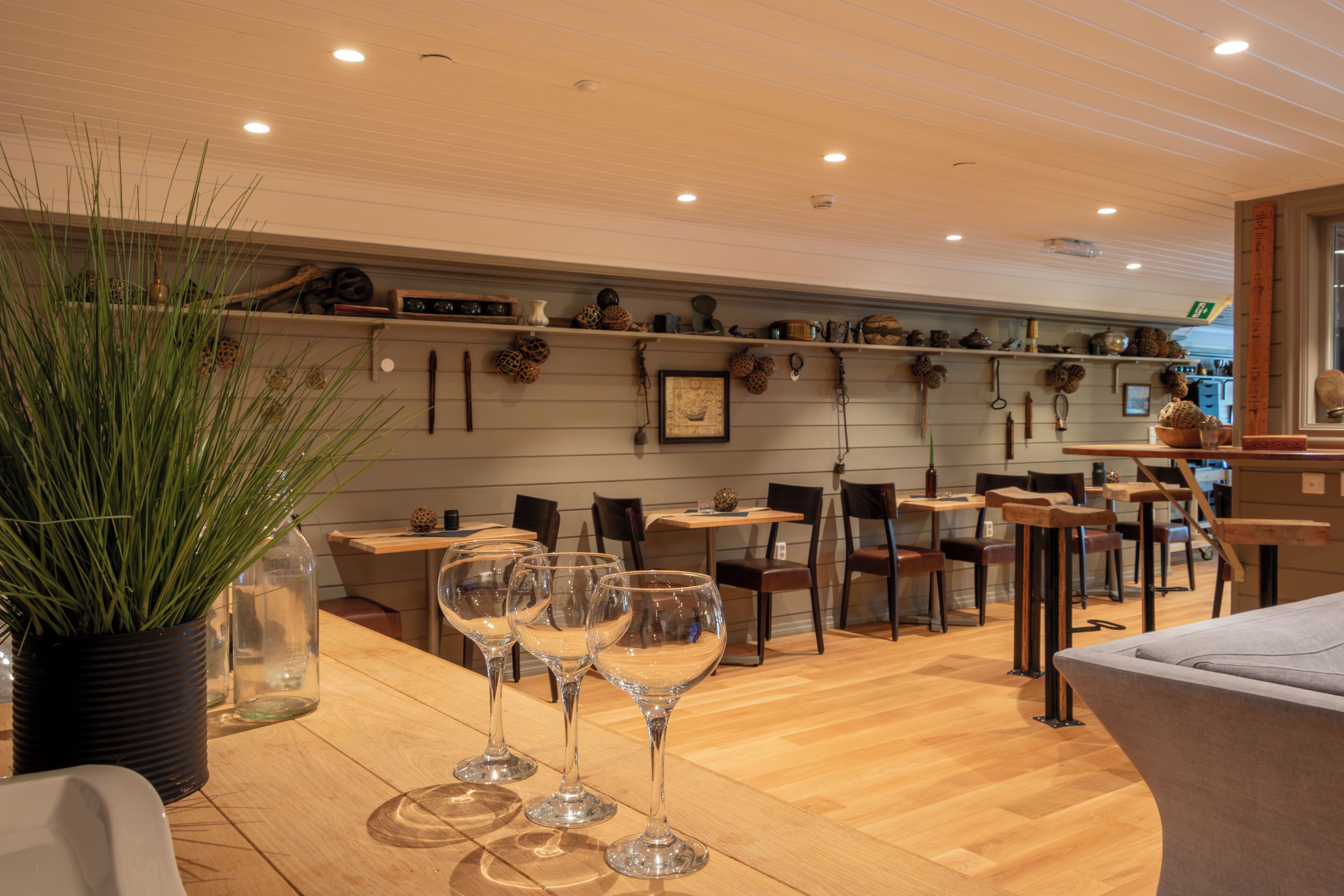 Un interior de restaurante con mesas y sillas de madera, y una planta en maceta.