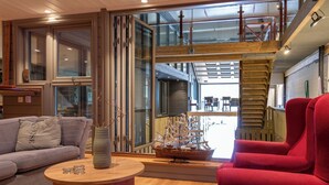 Interior moderno com escada de madeira, um modelo de navio e uma poltrona vermelha.