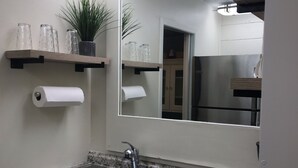A modern kitchen with granite countertops, a double sink, and a large mirror above the sink.