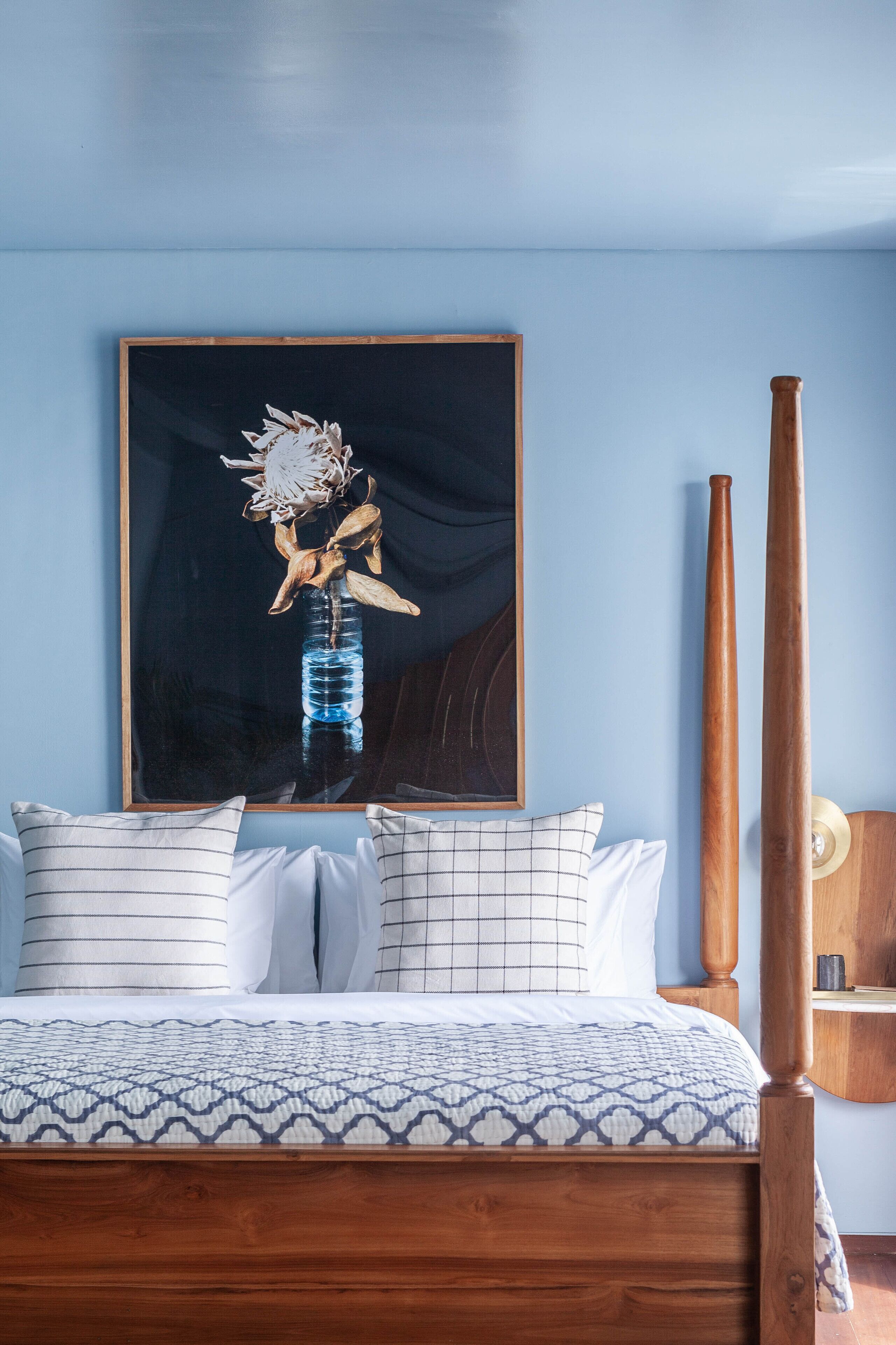 Une chambre à coucher avec un lit, des oreillers, un tableau encadré et un plancher en bois.