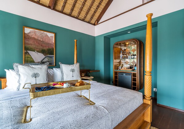 A bedroom with a bed, a tray with breakfast items, a wooden headboard, a mirror, and a painting on the wall.
