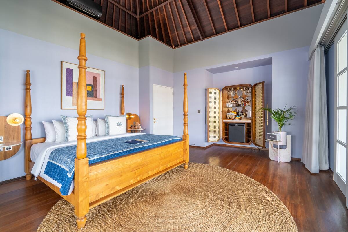 A spacious bedroom with a large wooden bed, a built-in wardrobe, and a large window.