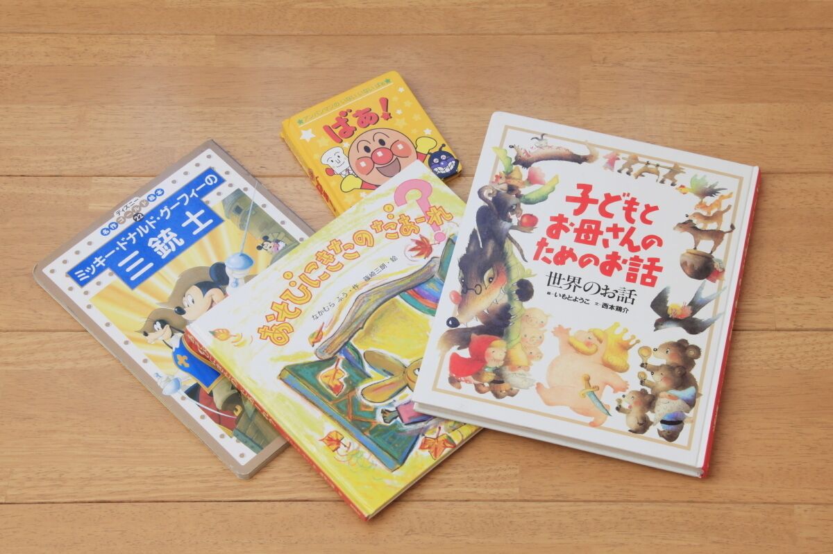Three books with Japanese text and colorful illustrations on a wooden surface.