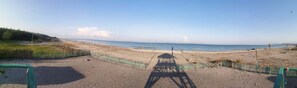 A beach with a wooden structure in the foreground, a fence, and a clear view of the ocean. - Camp Rofelio Surfing Beach Resort (San Felipe)