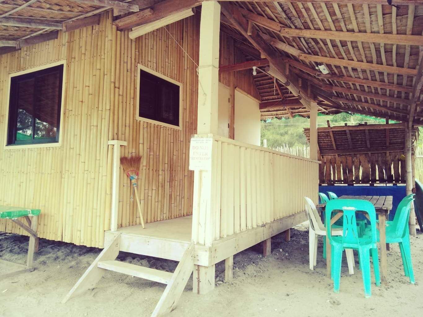 A wooden building with a covered porch, a small window, and a sign indicating a restricted area.