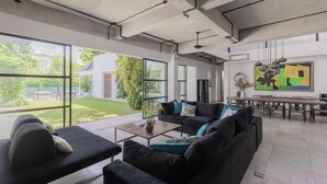 Een moderne woonkamer met een zwarte bank, een salontafel en een eetgedeelte met een grote tafel en stoelen.