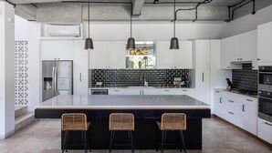 Een moderne keuken met een groot eiland, barstoelen en hanglampen.