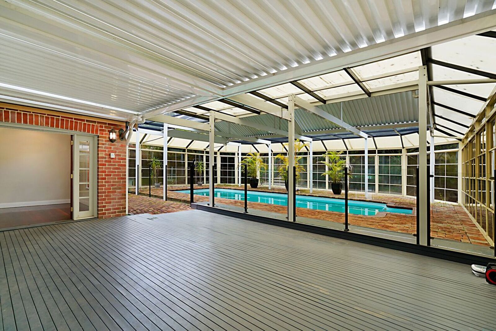 A covered outdoor area with a pool, wooden deck, and glass walls. - SPEERS POINT - Water Views, Pool, Sleeps 12, 8 Beds, Great for Families/groups (Speers Point)