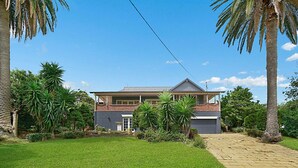 A two-story house with a brick facade, a front porch, and a well-maintained lawn. - SPEERS POINT - Water Views, Pool, Sleeps 12, 8 Beds, Great for Families/groups (Speers Point)
