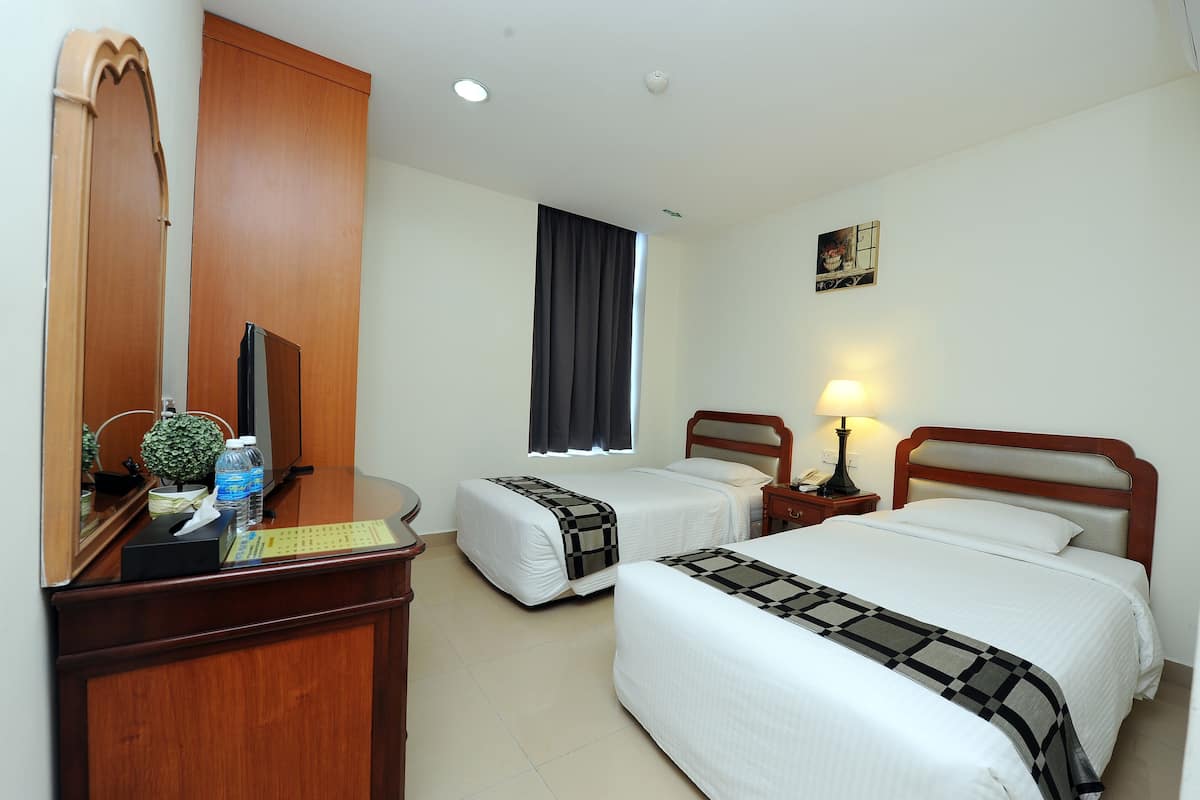 A hotel room with two beds, a desk with a mirror, a lamp, and a window with curtains.