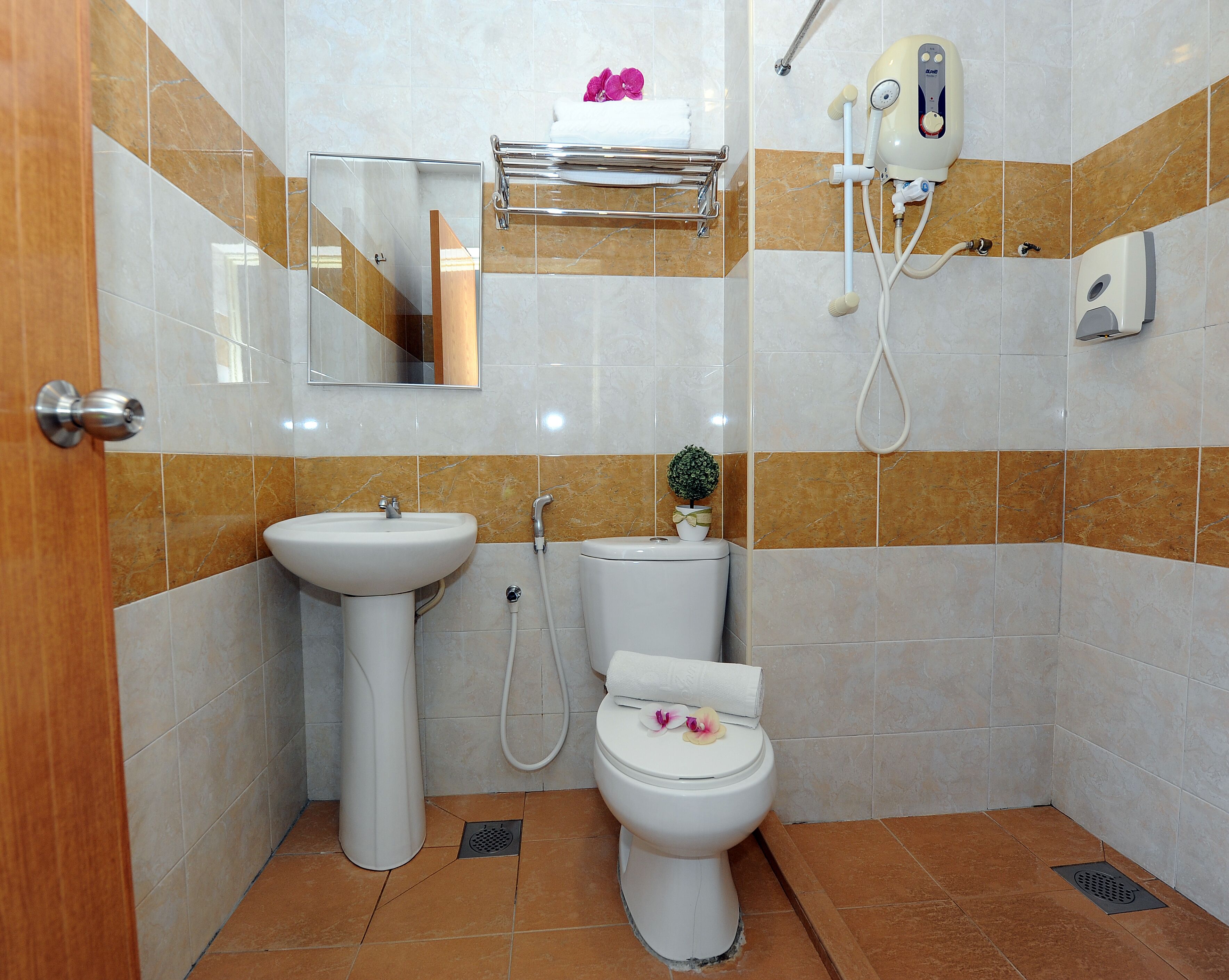 A bathroom with a sink, toilet, shower, and a mirror.