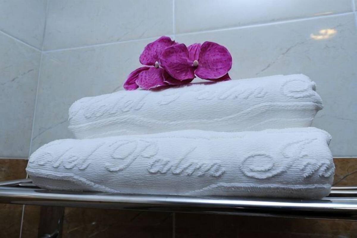 Two white towels with embossed text and a purple flower on a bathroom counter.