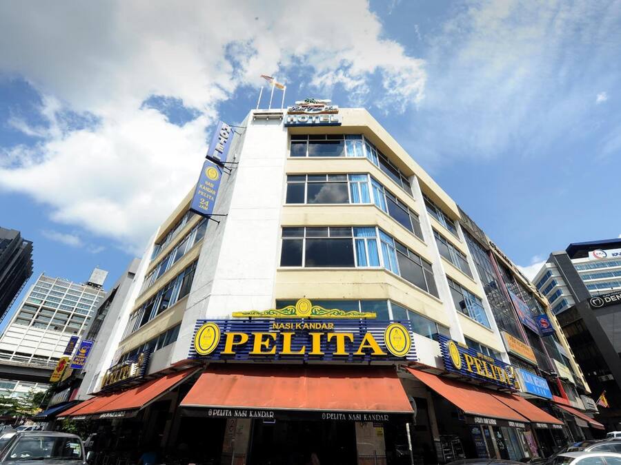 Un edificio de varios pisos con un llamativo letrero de 'PELITA' en la planta baja, que indica un hotel.