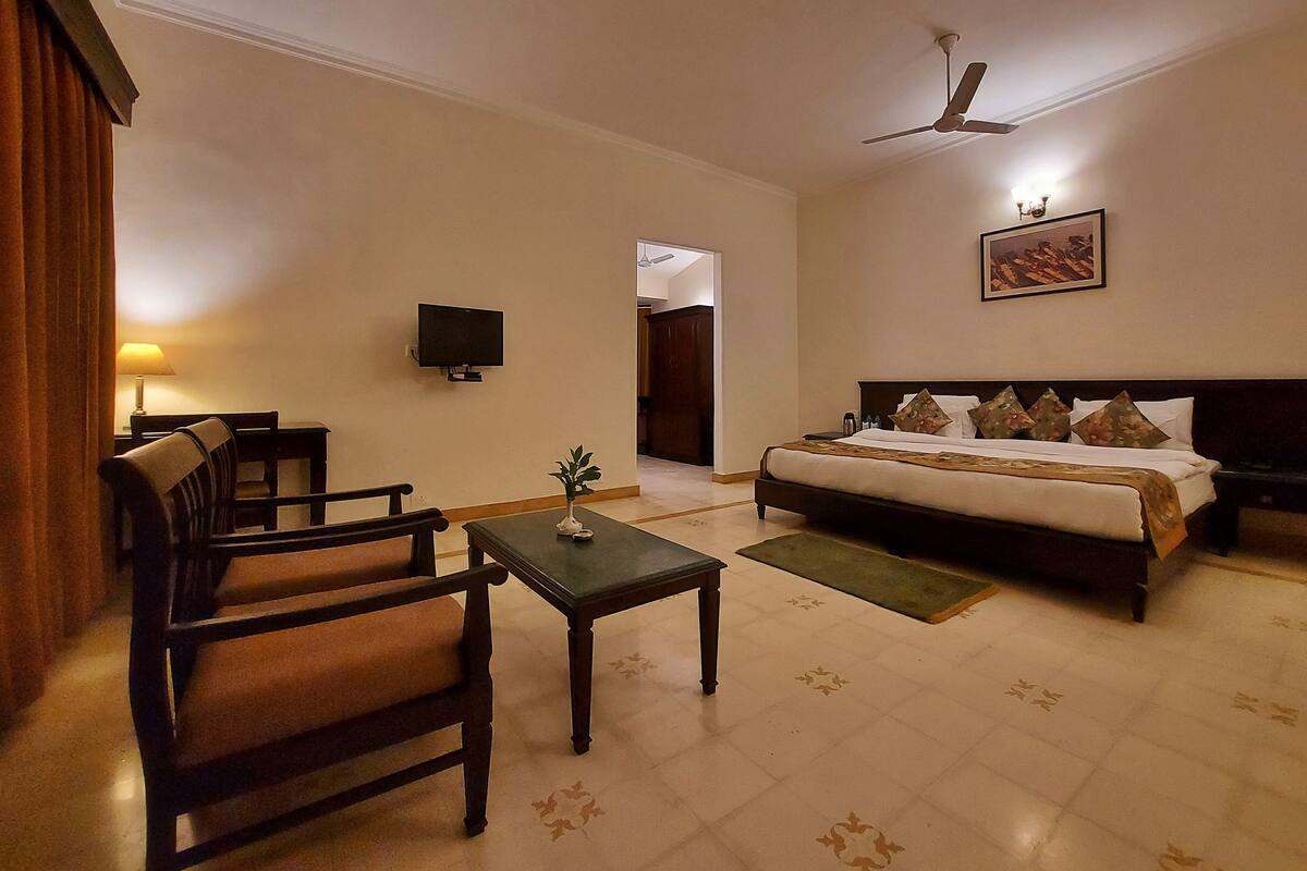 A hotel room with a bed, a desk, a chair, a television, and a ceiling fan.