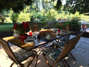 Un área de comedor al aire libre con una mesa de piedra, sillas y una variedad de vajilla.