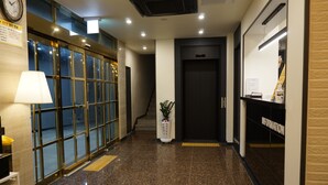 A hotel lobby with a reception desk, a staircase, and a glass door entrance. - Hotel Juno (Gangneung)