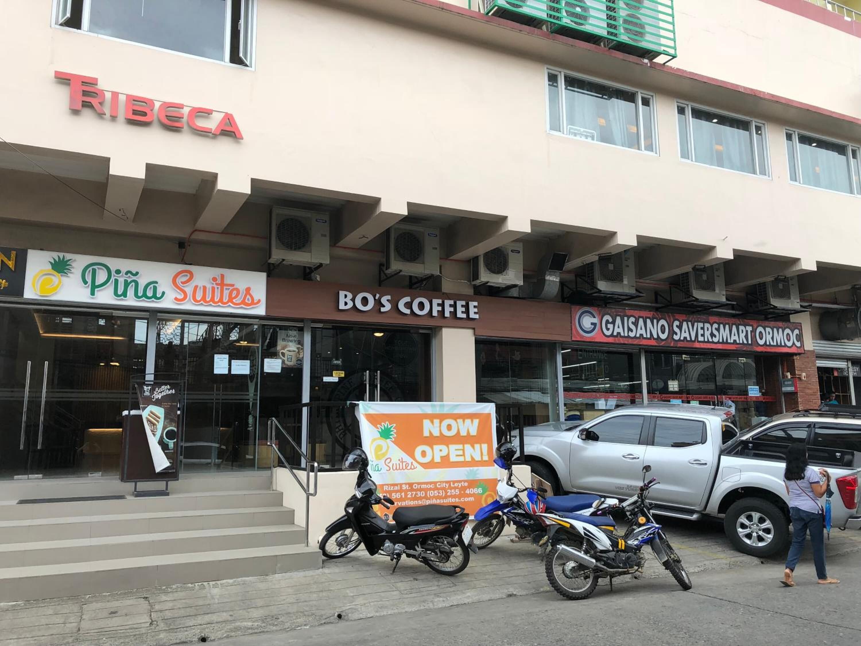 Un edificio con varios negocios, incluyendo 'Pina Suites', 'BO'S Coffee' y 'Gaisano Saversmart Ormoc'.