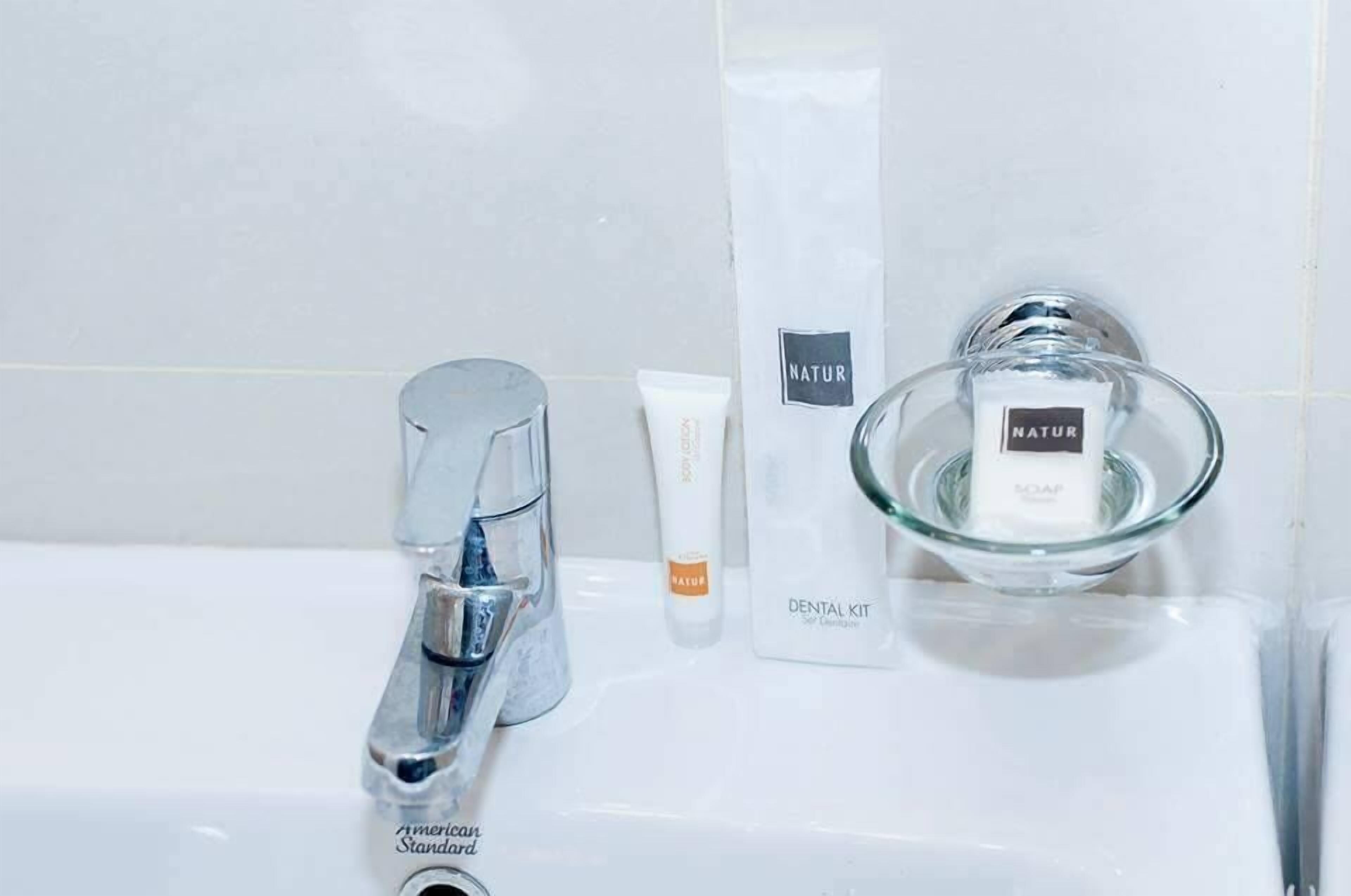 A bathroom sink with a chrome faucet, a tube of toothpaste, a bar of soap, and a glass soap dish.