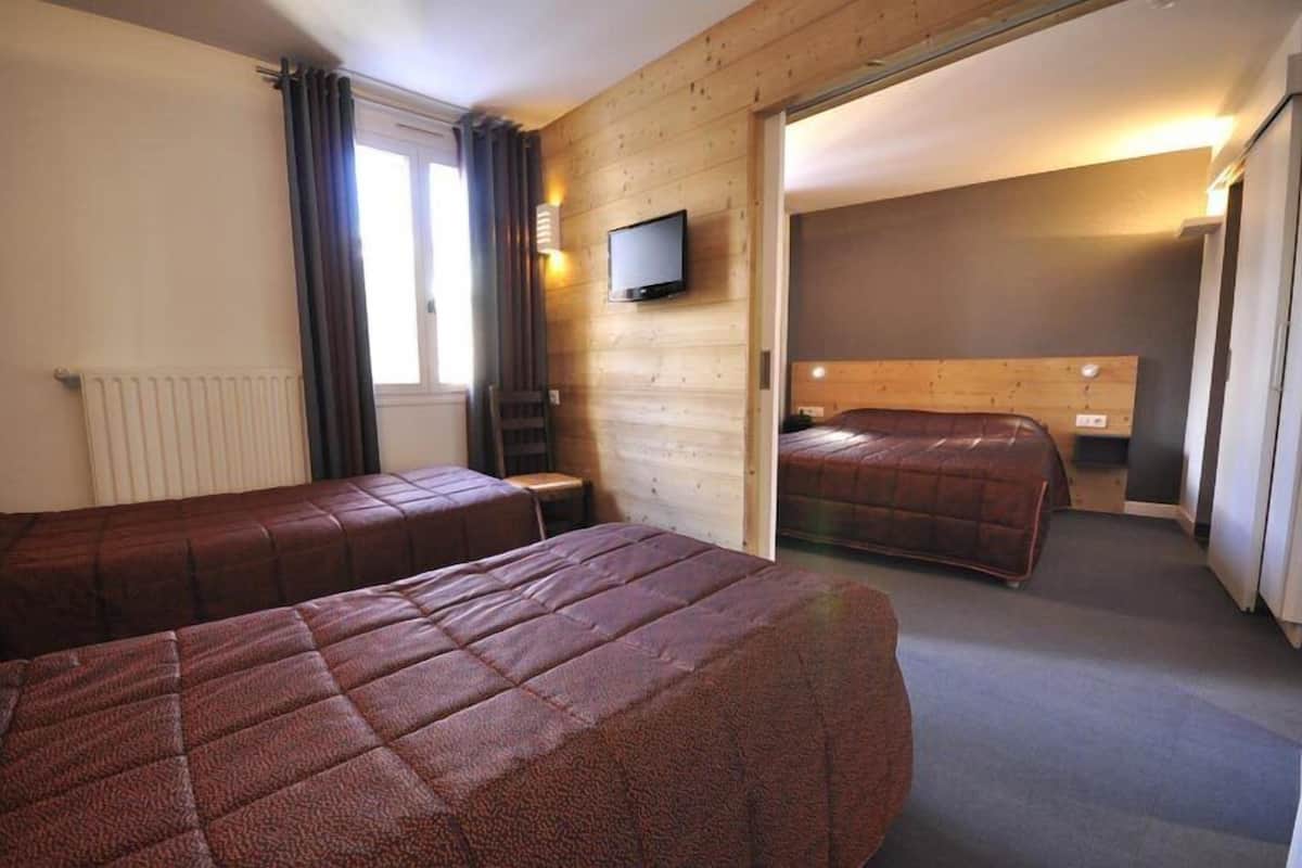 Ein Hotelzimmer mit zwei Betten, einem Fernseher und Holzmöbeln.