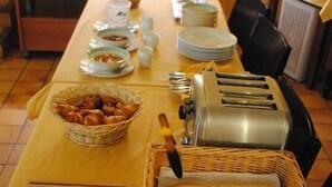 A breakfast buffet setup with bread, pastries, and a toaster. - Hôtel de l'Europe et des Bains (Monetier-les-Bains)