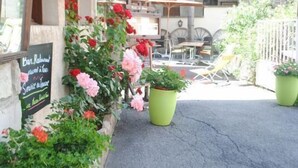 A restaurant with outdoor seating, large potted plants, and a chalkboard menu. - Hôtel de l'Europe et des Bains (Monetier-les-Bains)