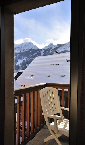A wooden deck with a white Adirondack chair overlooking a snowy mountain landscape. - Hôtel de l'Europe et des Bains (Monetier-les-Bains)