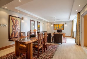 A spacious living room with a dining area, a television, and artwork on the walls.