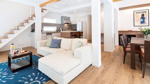 A modern living room with a sofa, coffee table, and a staircase leading to a kitchen. - Ajisai Chalet  (Kutchan)
