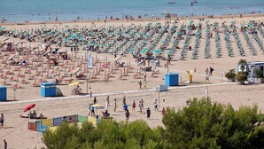 Ein Strand mit Liegestühlen und Sonnenschirmen, einem Rettungsturm und freiem Blick auf das Meer.