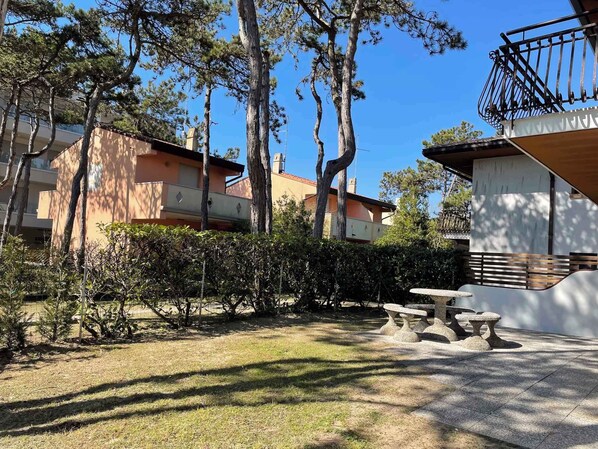 A courtyard with a stone bench, a small table, and a metal railing.