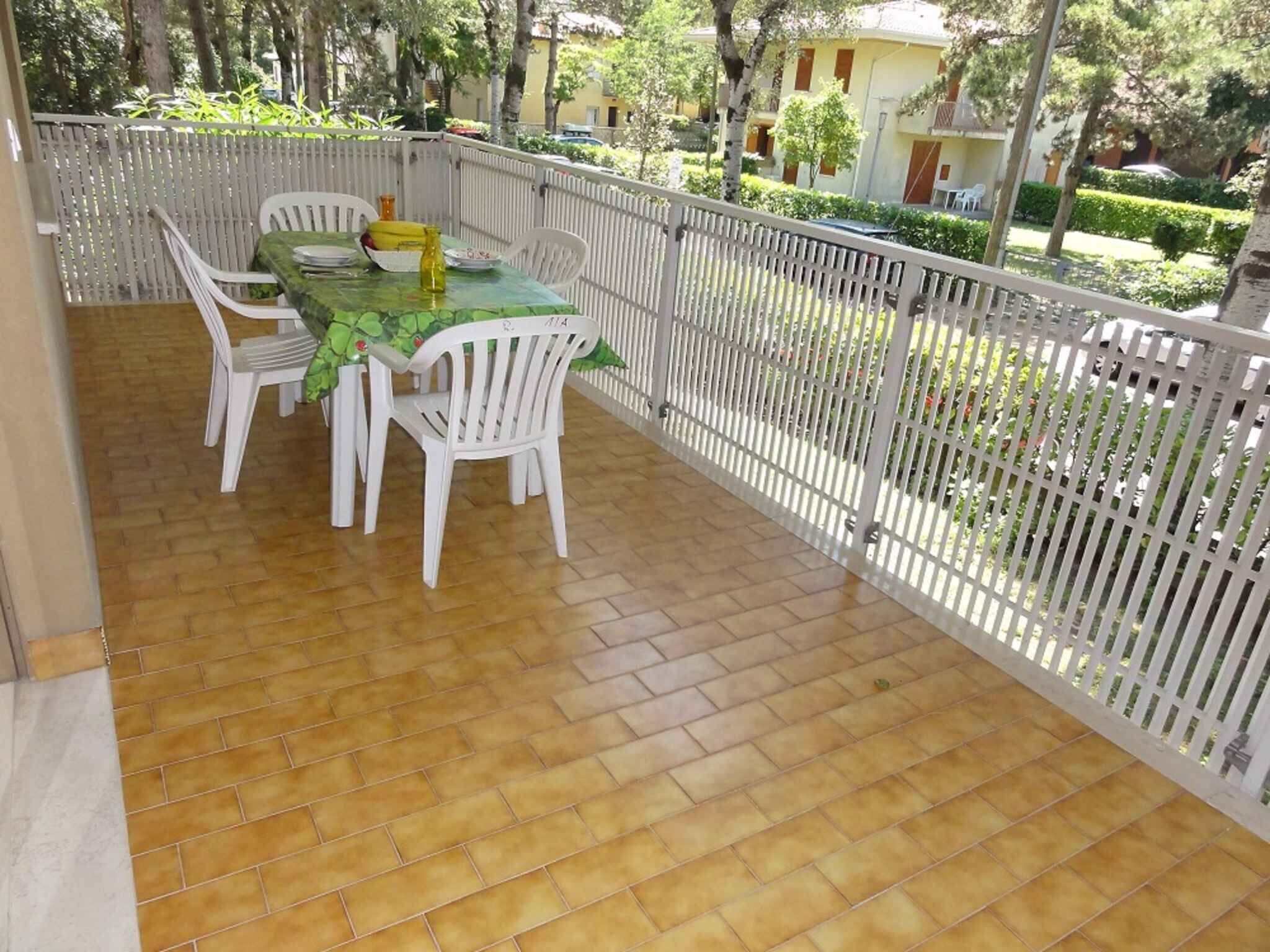 A covered patio with a tiled floor, a table with chairs, and a white fence.