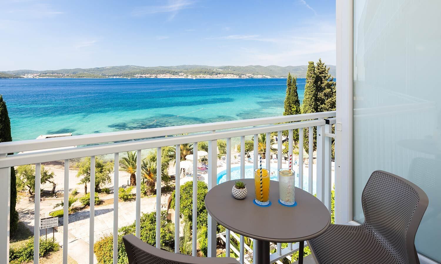 A balcony with a view of a beach and pool area.