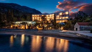 Um hotel com várias varandas, piscina e montanhas ao fundo.