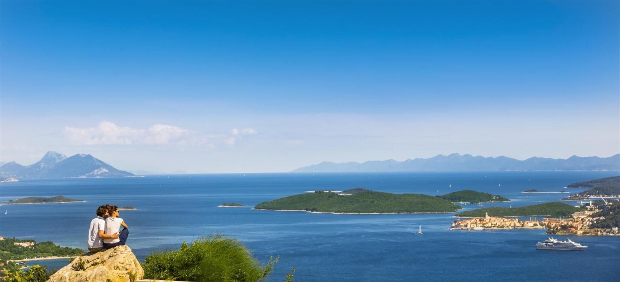 Un paisaje costero con vista despejada al mar, varias islas y montañas distantes.