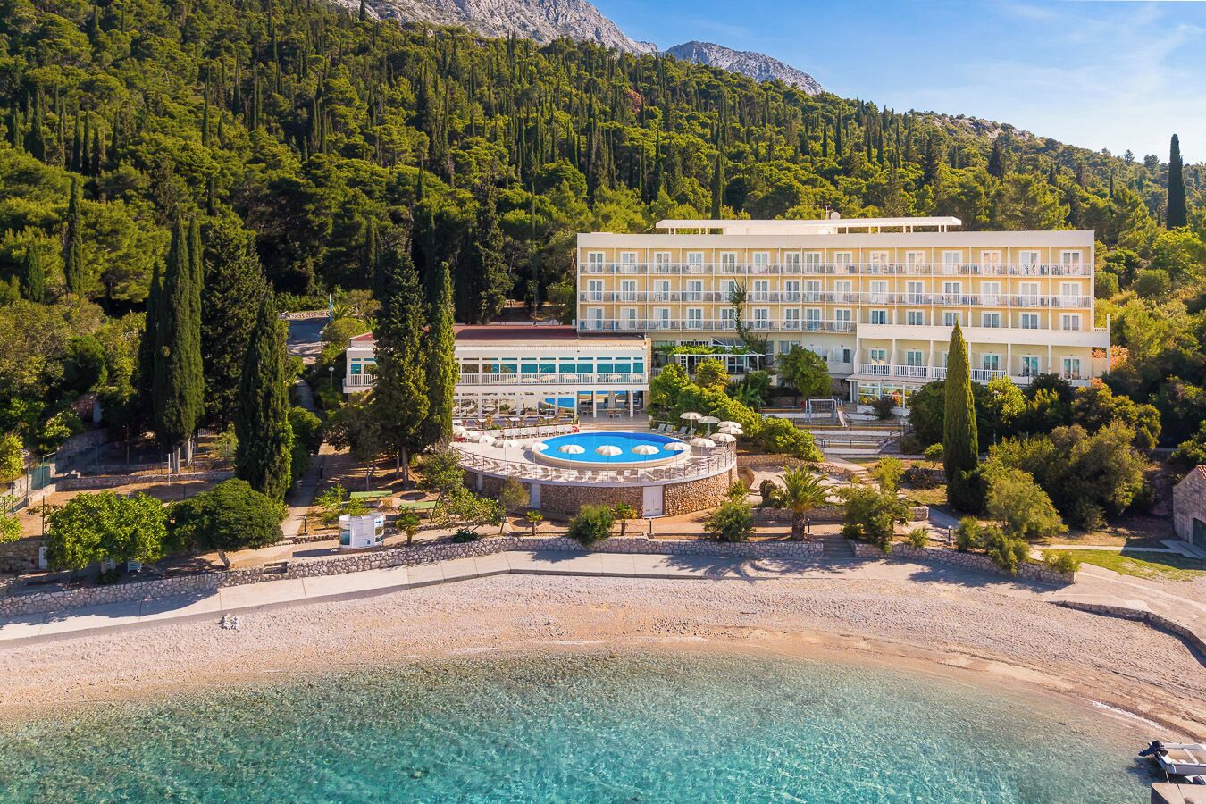 A hotel with a pool, surrounded by trees and mountains.