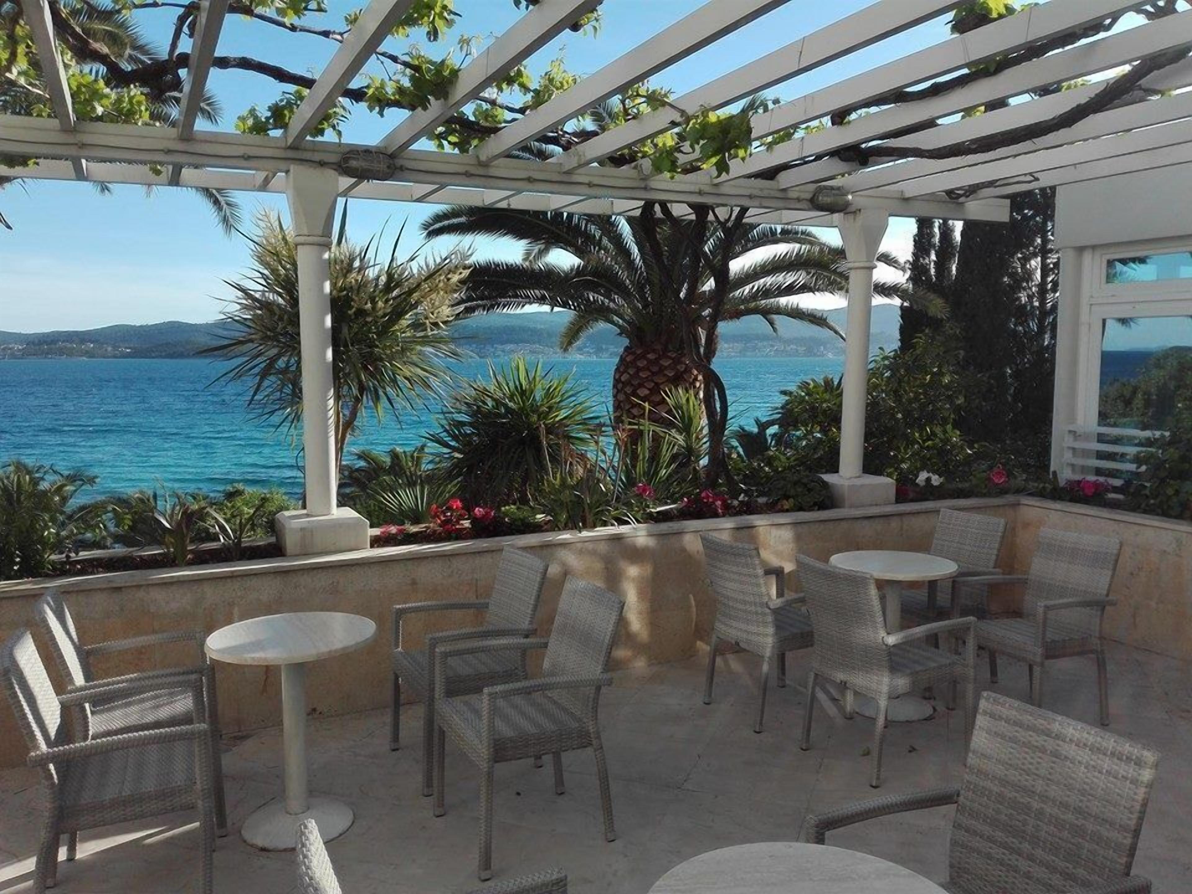 Un patio al aire libre con mobiliario de mimbre y vistas al mar.