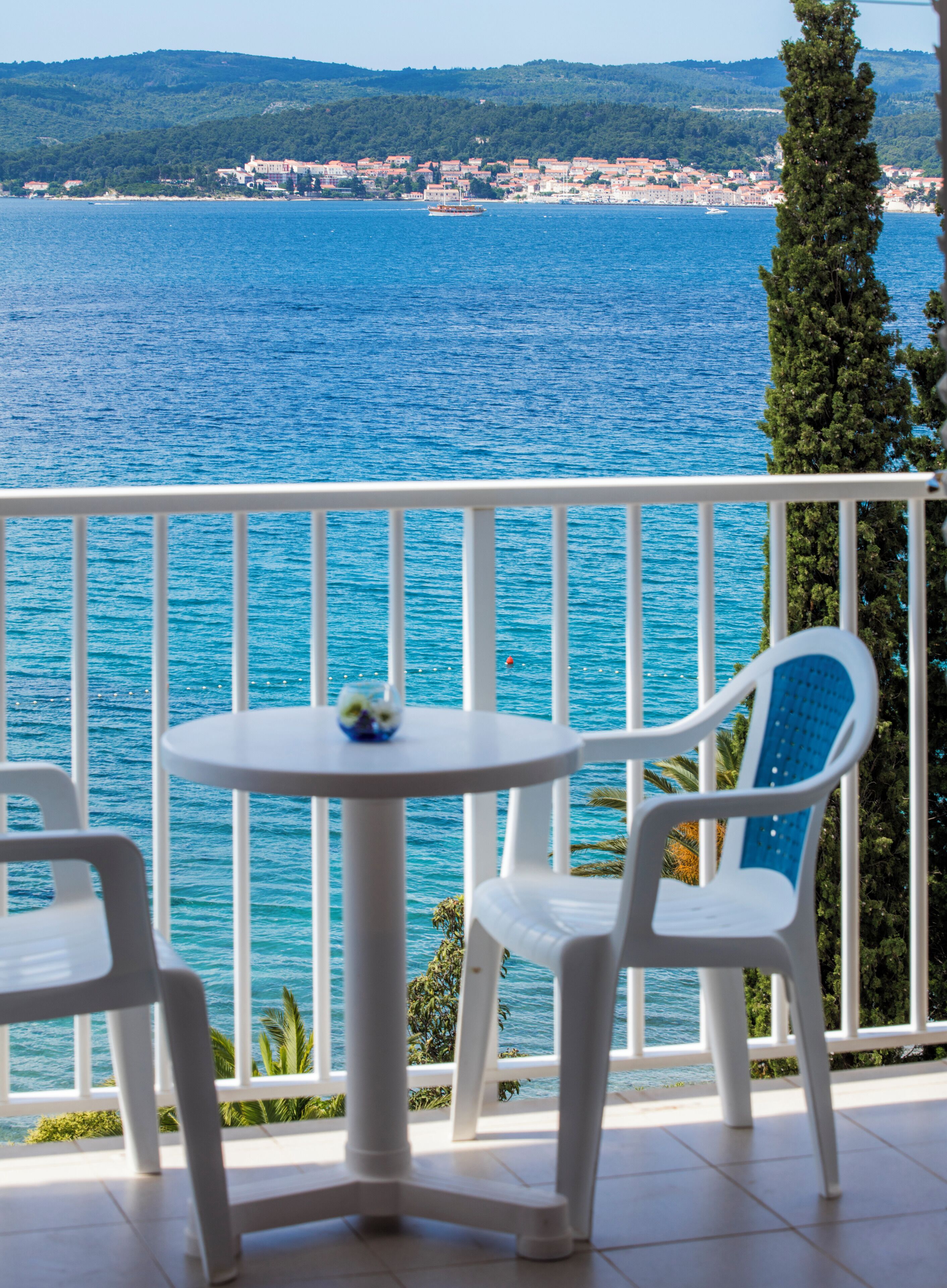 Un balcon avec vue sur la mer et sur une ville située au loin.