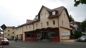 Ein Gebäude mit roter und beiger Fassade, einem Schild mit der Aufschrift "Wendler" und einem sichtbaren Eingang.