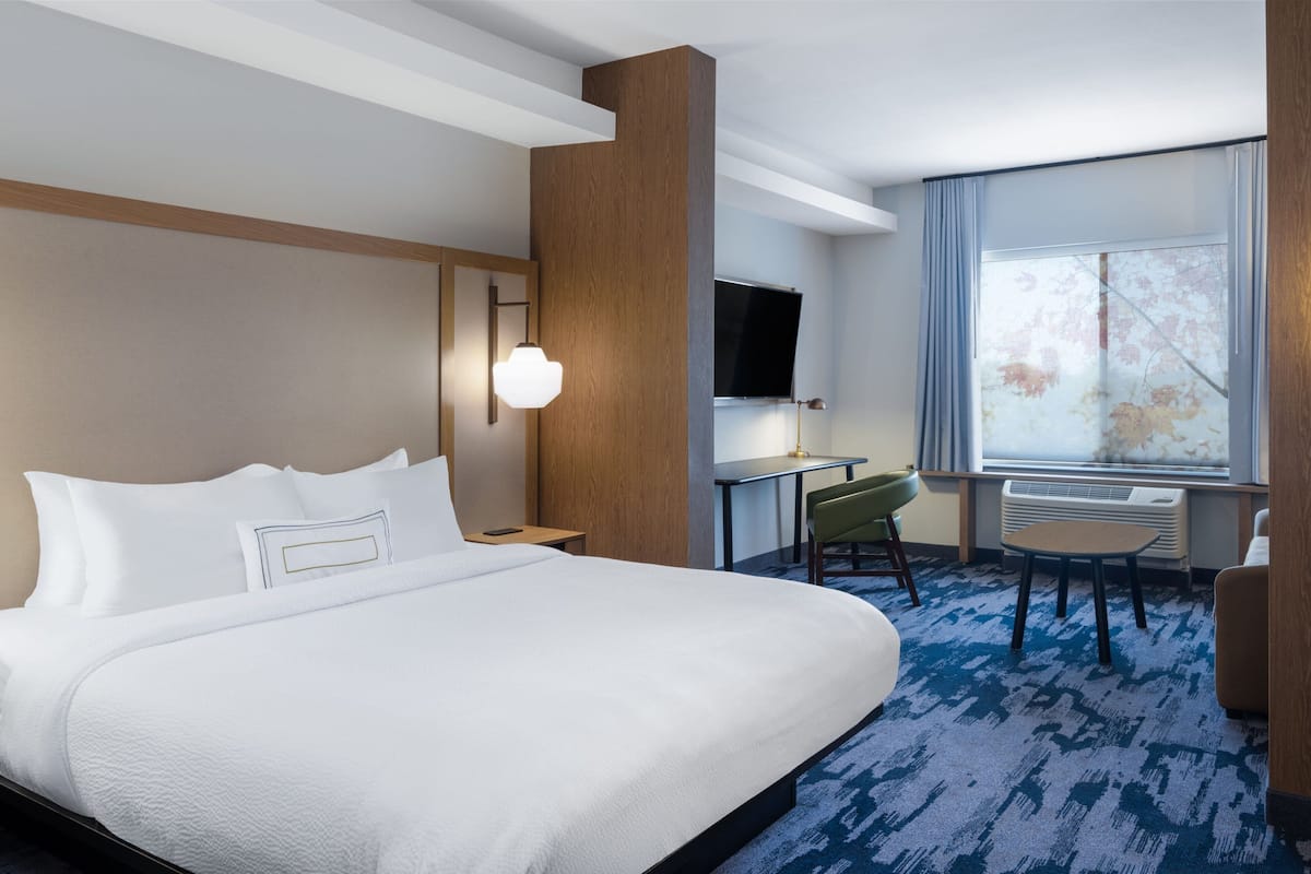 Habitación de hotel con una cama grande, un escritorio, una silla, un televisor y una ventana con vistas.