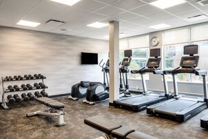 Un gimnasio con cintas de correr, mancuernas y bancos de pesas.