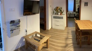 A living room with a TV, a wooden coffee table, a dining table, and a potted plant. - Szigeti Ház, Szécsisziget (Deák Ferenc utca)